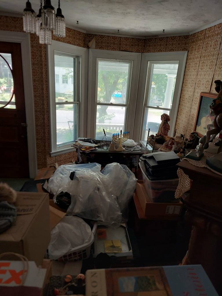 a large bay window backgrounds a semi-cluttered room