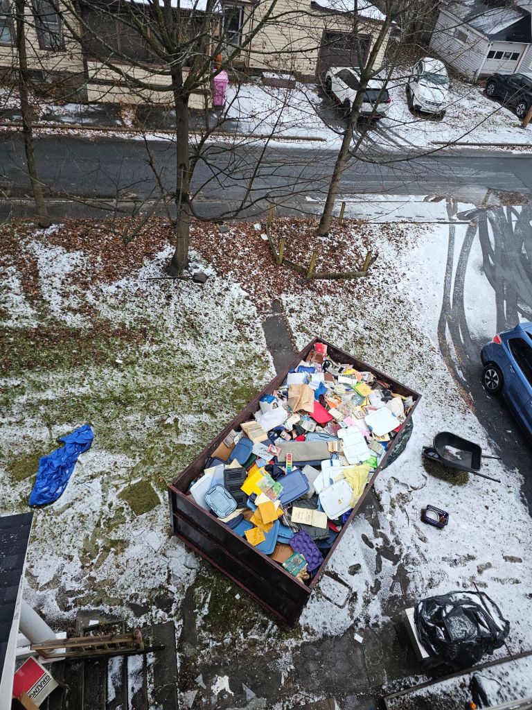 an overhead view of a mostly full 20-yard dumpster, in a yard with a light dusting of snow